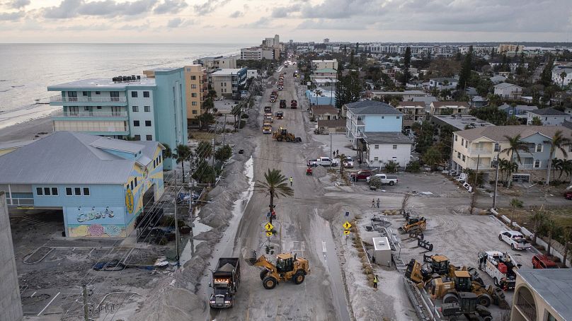 Crews work to clean up the tons of sand and debris pushed onto Gulf Boulevard from Hurricane Helene storm surge.