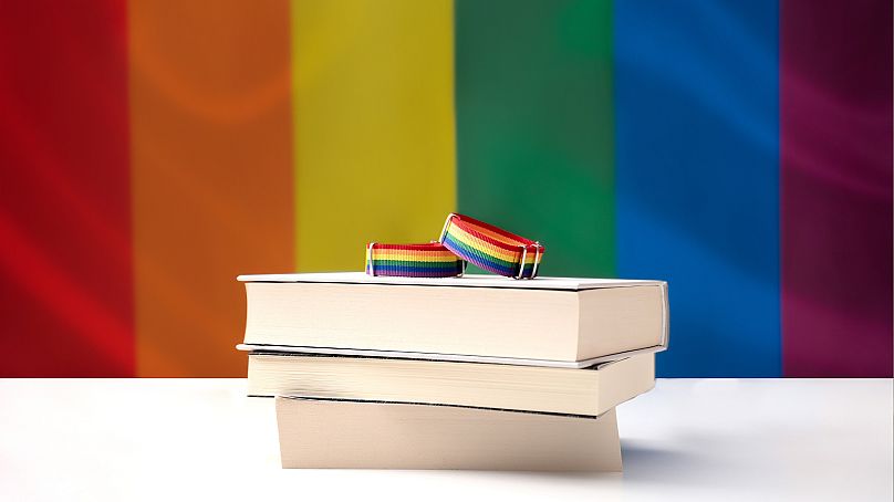 Pile of books in front of a rainbow flag