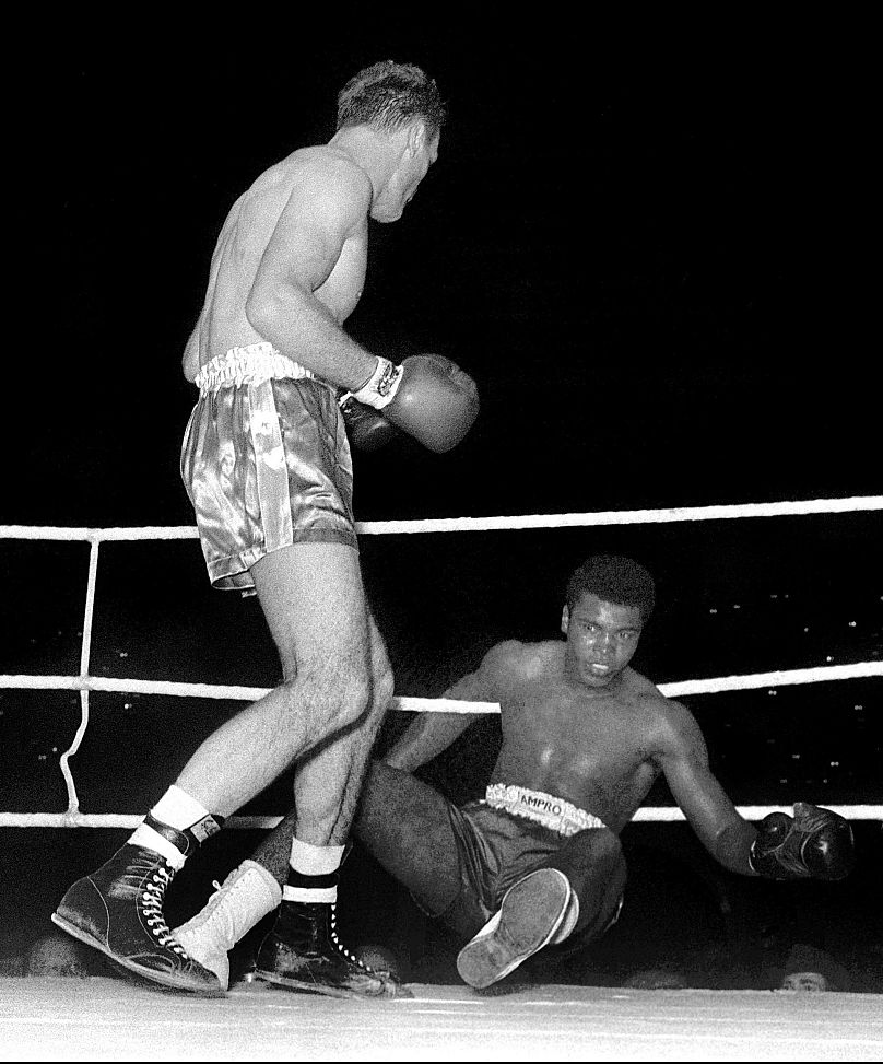 Muhammad Ali, being knocked down by Henry Cooper during their boxing match at Wembley, London.