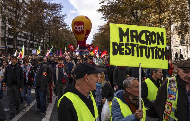 Un manifestante tiene un cartello con la scritta “Destituzione di Macron” durante un corteo contro il nuovo governo del premier francese Michel Barnier, Parigi, 1 ottobre 2024