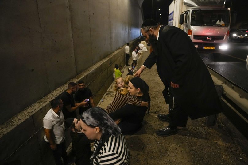 People take cover on the side of a road as a siren sounds a warning of incoming missiles fired from Iran on a freeway in Shoresh, between Jerusalem and Tel Aviv in Israel 