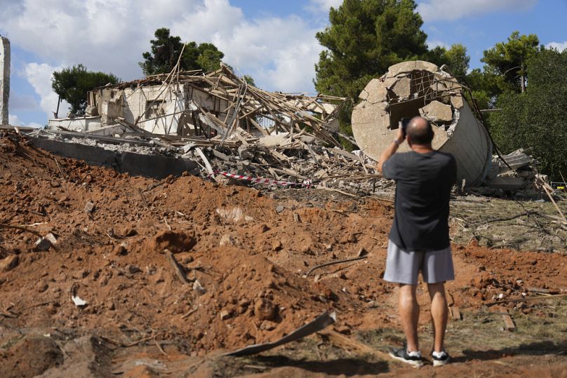 Un homme photographie un bâtiment détruit par un missile iranien dans la ville de Hod Hasharon, le 2 octobre 2024 (AP Photo/Ariel Schalit)