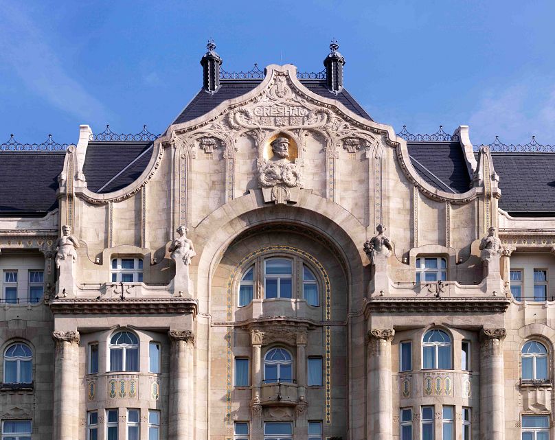Az épület névadója a homlokzatról néz le a budapesti panorámára 