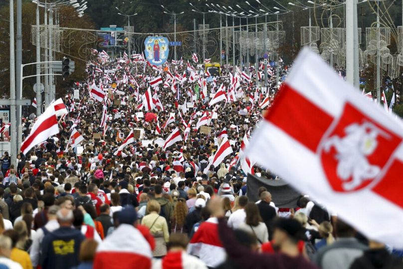 Manifestantes com bandeiras nacionais bielorrussas antigas marcham em Minsk, Bielorrússia, no domingo, 6 de setembro de 2020.