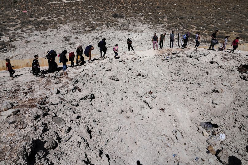 Families cross into Syria through a crater caused by Israeli airstrikes aiming to block Beirut-Damascus highway at Masnaa crossing, in the Bekaa Valley, Lebanon, Oct. 5 2024