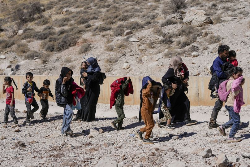 Families cross into Syria through a crater caused by Israeli airstrikes aiming to block Beirut-Damascus highway at Masnaa crossing, in the Bekaa Valley, Lebanon, Oct. 5 2024