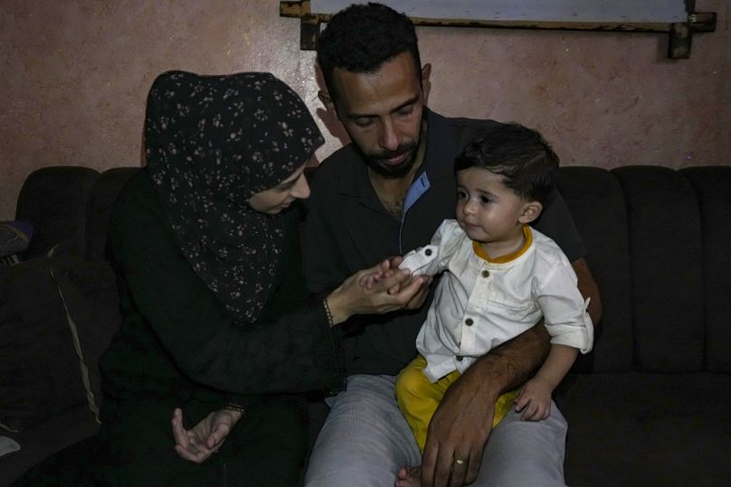 أمل ومصطفى الطويل يلعبان مع طفلهما علي، الذي ولد في 7 أكتوبر، في منزلهما بالنصيرات، قطاع غزة، السبت، 5 أكتوبر، 2024.