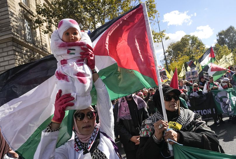 Um manifestante segura uma boneca pintada com sangue falso durante uma manifestação de apoio à Palestina e ao Líbano em Paris, a 5 de outubro de 2024