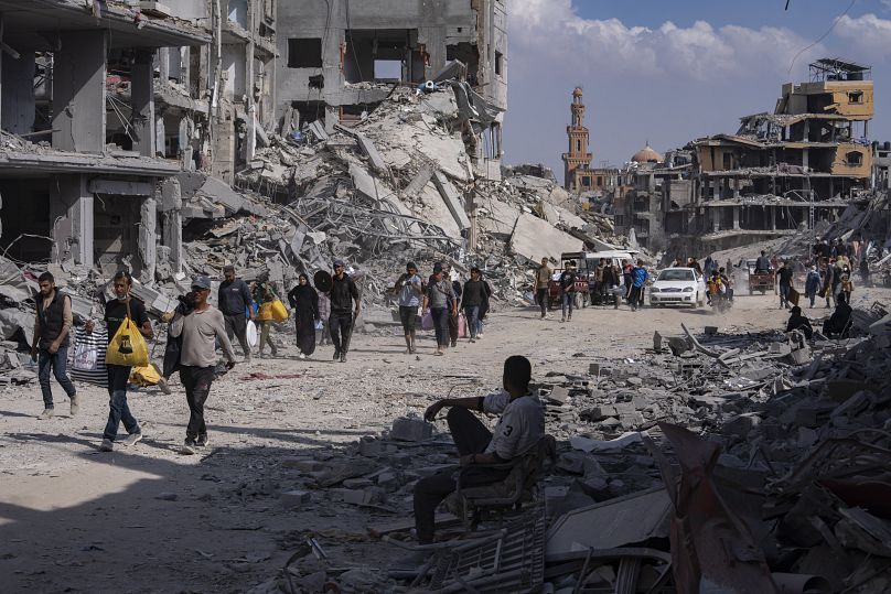 Palestinianos caminham entre os escombros na sequência de uma ofensiva aérea e terrestre israelita em Khan Younis, 8 de abril de 2024