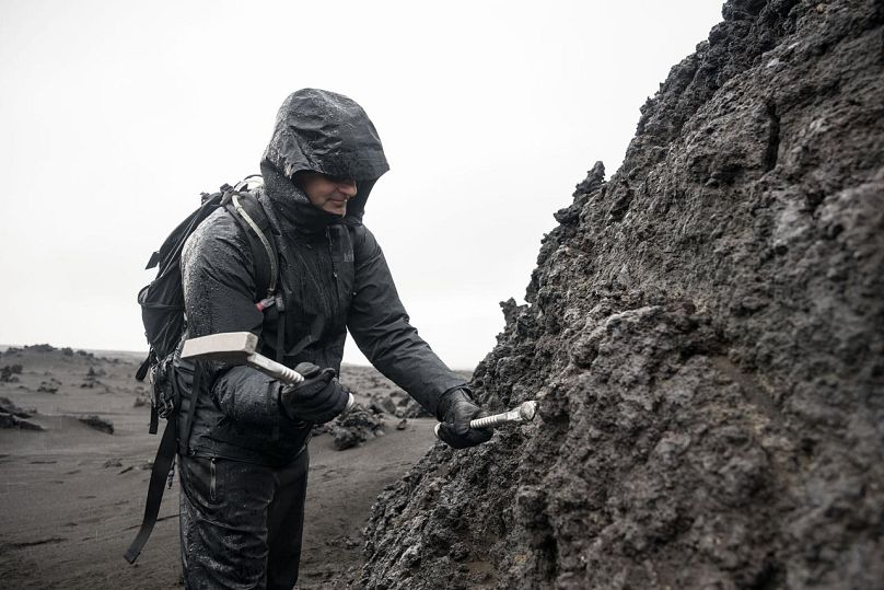 CSA (Canadian Space Agency) astronaut and Artemis II crew member Jeremy Hansen uses a rock hammer to break a sample of rock during a training exercise in Iceland 