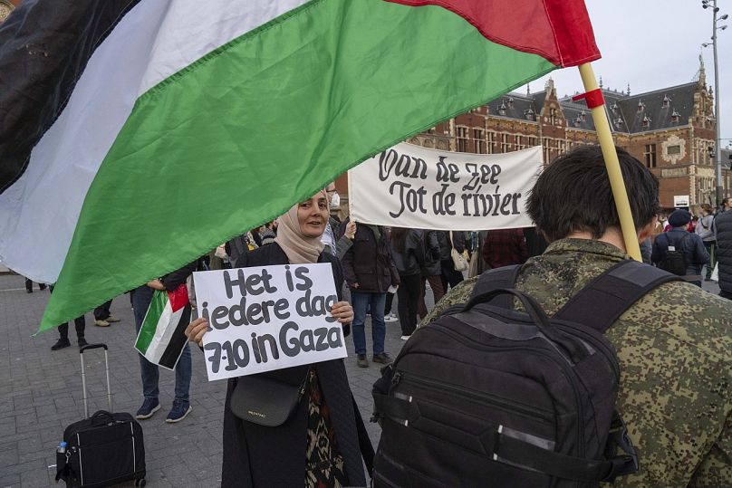 Filistin yanlısı bir gösterici, Amsterdam'daki bir gösteri sırasında "Gazze'de Her Gün 7 Ekim" yazılı pankart taşıyor, 7 Ekim 2024.