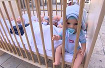 Baby doll in wooden crib outside of Nyugati train station in Budapest, Hungary.
