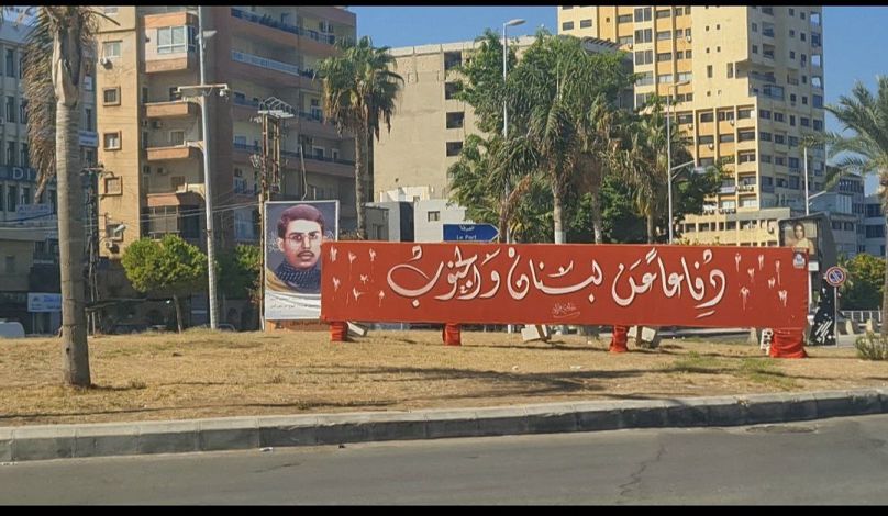 شوارع مدينة صور خالية أثناء الحرب وتظهر لافتة في مكتوب عليها "دفاعا عن لبنان والجنوب" وخلفها صورة ل"أحمد قصير" وهو مقاتل من حزب الله