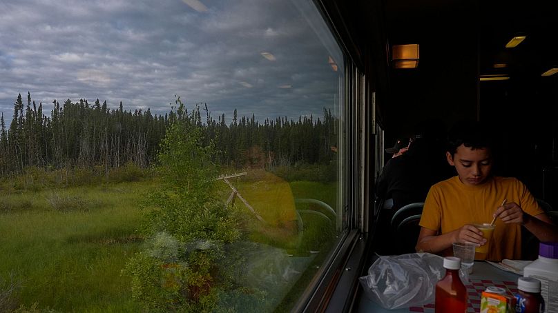 Um passageiro dorme na carruagem económica de um comboio na sexta-feira, 9 de agosto de 2024, perto de Ilford, Manitoba.  