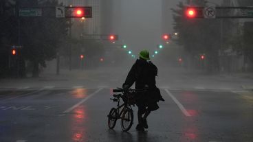 A man walks through windy and rainy conditions on a deserted street in downtown Tampa.