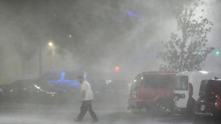 A man walks through windy and rainy conditions on a deserted street in Tampa.
