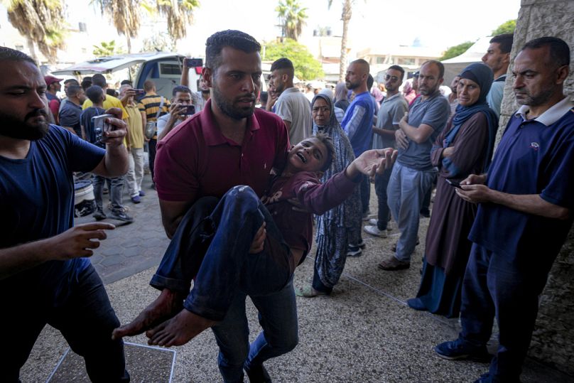 رجل فلسطيني يحمل طفلًا مصابًا بعد غارة جوية إسرائيلية في دير البلح، قطاع غزة، الخميس، 10 أكتوبر/تشرين الأول 2024. 