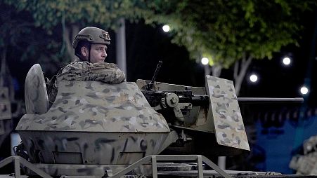 FILE: A Lebanese army soldier sits behind his weapon atop of an APC at the site of an Israeli airstrike in Beirut's southern suburb, 23 September 2024