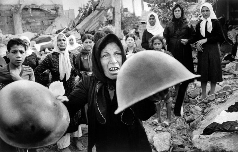 FILE - In this Sept. 27, 1982 file photo, a Palestinian woman brandishes helmets during a memorial service in Beirut for victims of Lebanon's Sabra refugee camp massacre. 