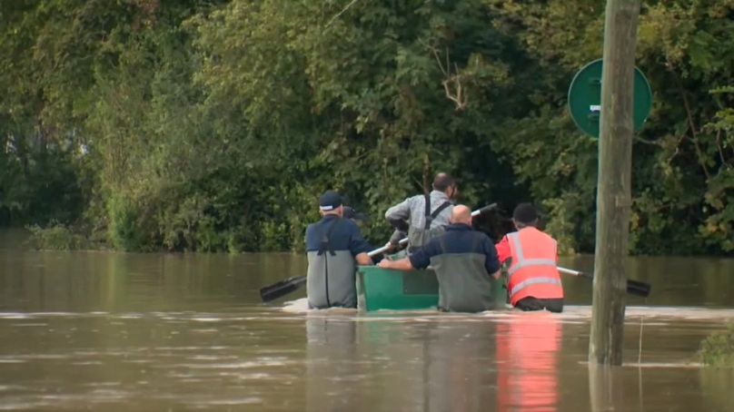 Uomini attraversano una strada sommersa dall'acqua in Francia, 10 ottobre 2024