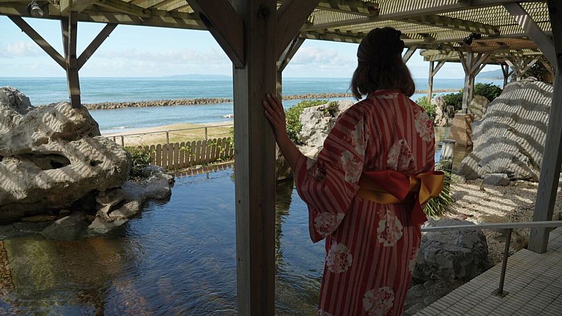 Euronews journalist Anca Ulea wears a yukata and looks out at the Sea of Japan at Taikanso Senami no Yu
