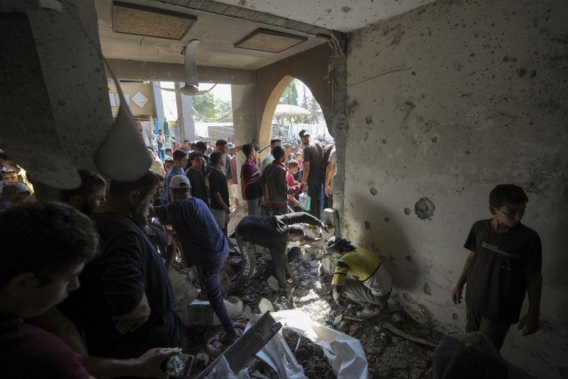 فلسطينيون يبحثون عن جثث أقاربهم الذين قُتلوا في قصف إسرائيلي على مدرسة في دير البلح، قطاع غزة