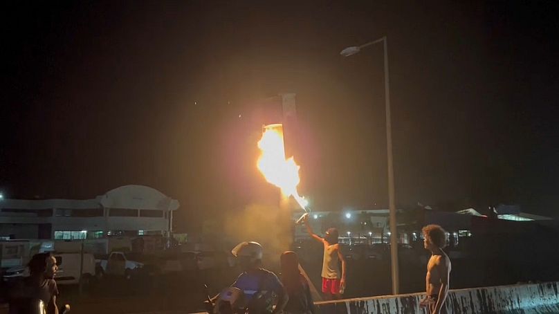Manifestantes prenden fuego a una señal de tráfico frente al aeropuerto de Fort-de-France en Martinica, 11 de octubre de 2024.