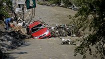 Un uomo usa una motosega per tagliare i ceppi d'albero e liberare un'auto lavata a valle dalla recente alluvione ad Arges, 30 luglio 2024.