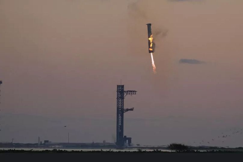 Il mega razzo booster di SpaceX torna sulla rampa di lancio per essere catturato durante un volo di prova domenica 13 ottobre 2024 a Boca Chica, in Texas.