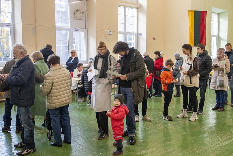 People queue to cast their ballots at a polling station during the first round of voting in parliamentary election in Vilnius, 13 October, 2024