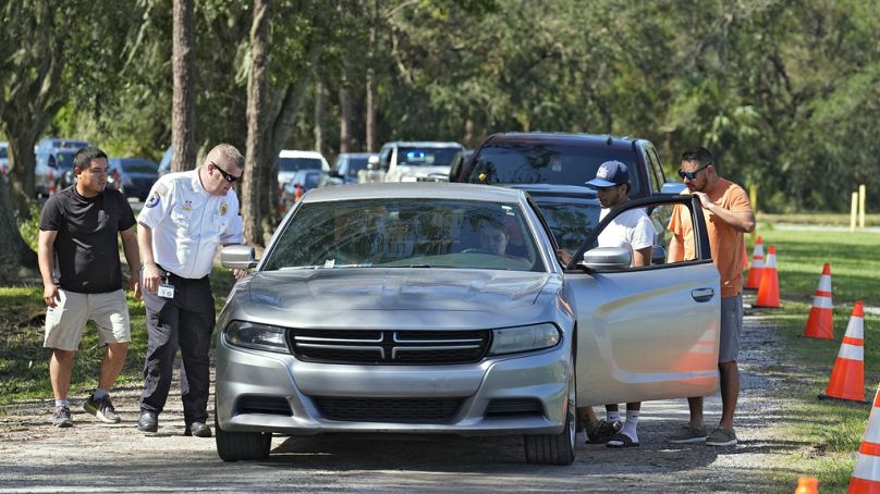 Law enforcement members help a motorist that ran out of fuel while waiting for in line for fuel at a depot on Saturday in Plant City, Florida