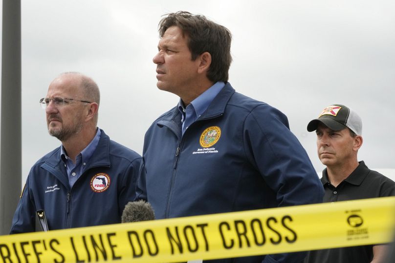 Ron DeSantis, centre, takes questions during a news conference in front of a St. Lucie County Sheriff's parking facility in Florida after Milton hit