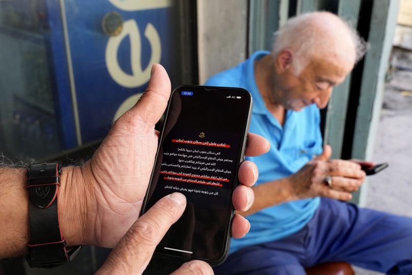 Men read mobile phone alerts telling residents of southern Lebanon not to return to their homes until further notice.