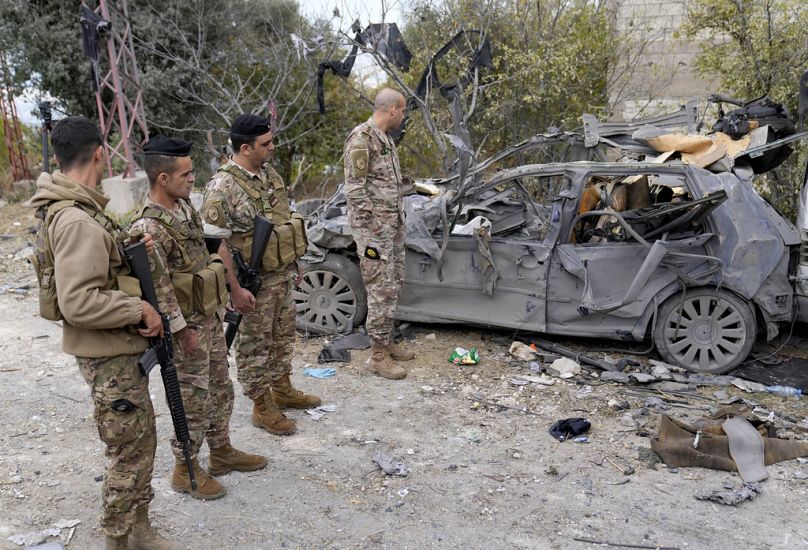 Soldati dell'esercito libanese in piedi accanto a un veicolo distrutto sul sito del bombardamento aereo israeliano nel villaggio di Ito, Libano settentrionale