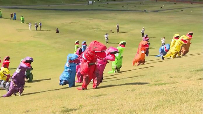 Runners roar up ski slope in colourful dinosaur costumes in Japan