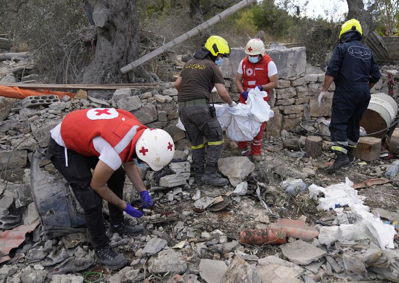 متطوعو الصليب الأحمر اللبناني وعمال الدفاع المدني يبحثون بين أنقاض مبنى مدمر بعد غارة جوية إسرائيلية يوم الاثنين في قرية أيتو، شمال لبنان.