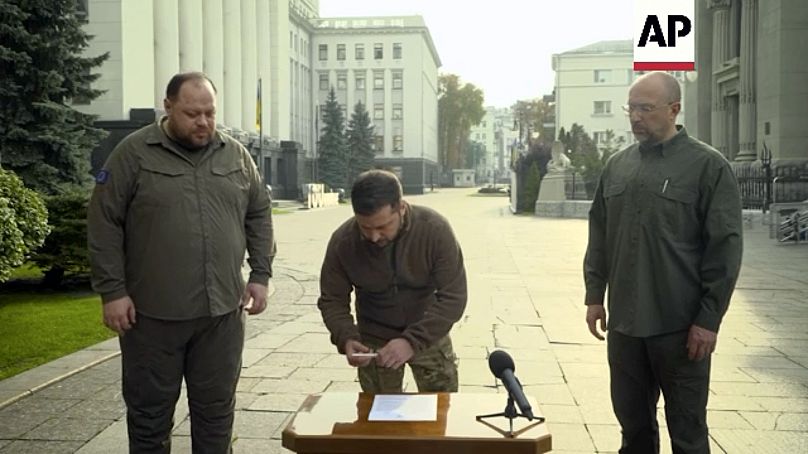 In questa immagine tratta dal video, Volodymyr Zelensky, insieme al premier ucraino e al capo della Verkhovna Rada, firma la richiesta di adesione accelerata alla Nato