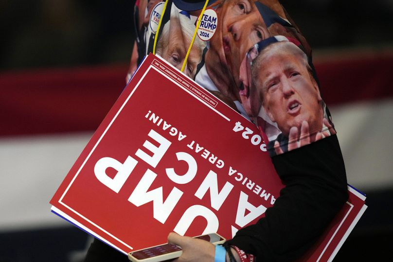 Un simpatizante porta pancartas tras un acto de campaña de Trump en Carolina del Norte.