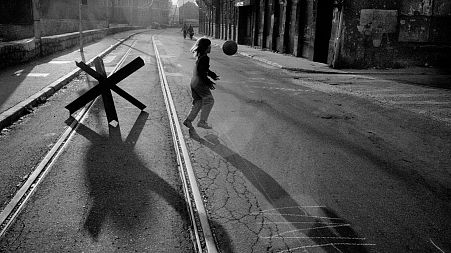  A young girl plays with a ball in the street alongside the River Miljack