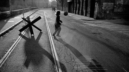  A young girl plays with a ball in the street alongside the River Miljack