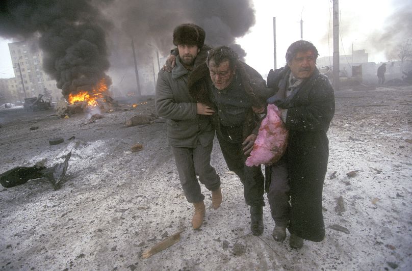 A wounded civilian is helped to safety after a Russian bombing attack that killed 18 people, including American photographer Cynthia Elbaum