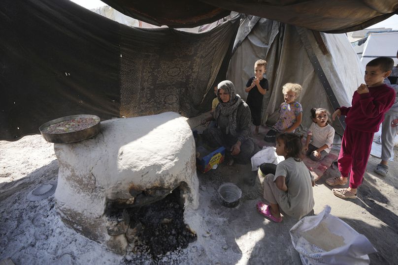 سيدة فلسطينية وأطفالها تحاول ان تحضر لهم طعاما وسط تجويه ممنهج يفرضه الجيش الإسرائيلي