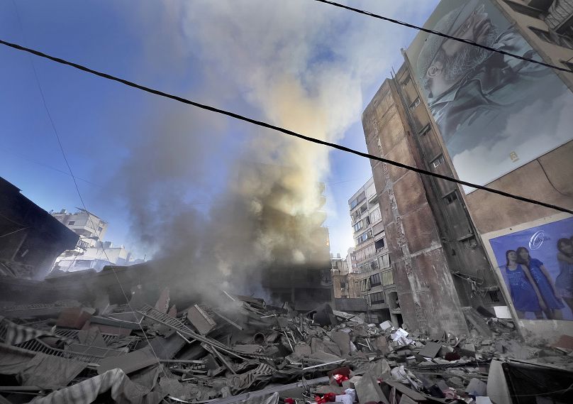 Lübnan'ın başkenti Beyrut'ta İsrail hava saldırısında vurulan yıkılmış bir binadan, Hizbullah komutanı İmad Muğniye'nin portresi yakınında duman yükseliyor, 20 Ekim 2024.