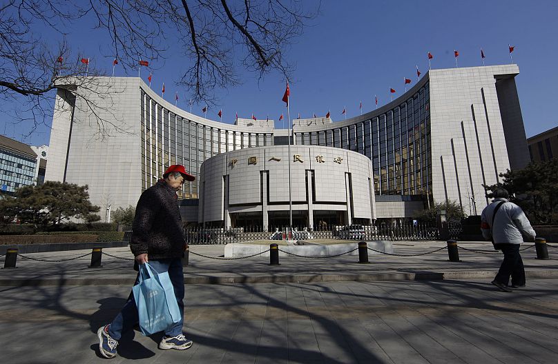 Sur cette photo prise le 12 mars 2012, un Chinois marche devant la banque centrale de Chine à Pékin, en Chine.