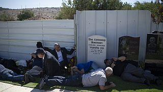 People take cover as a siren warns of incoming rockets during the funeral of Alexei Popov
