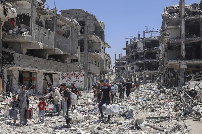 فلسطينيون يسيرون في الدمار الذي خلفه الهجوم الجوي والبري الإسرائيلي في جباليا شمال قطاع غزة في 30 مايو/أيار 2024