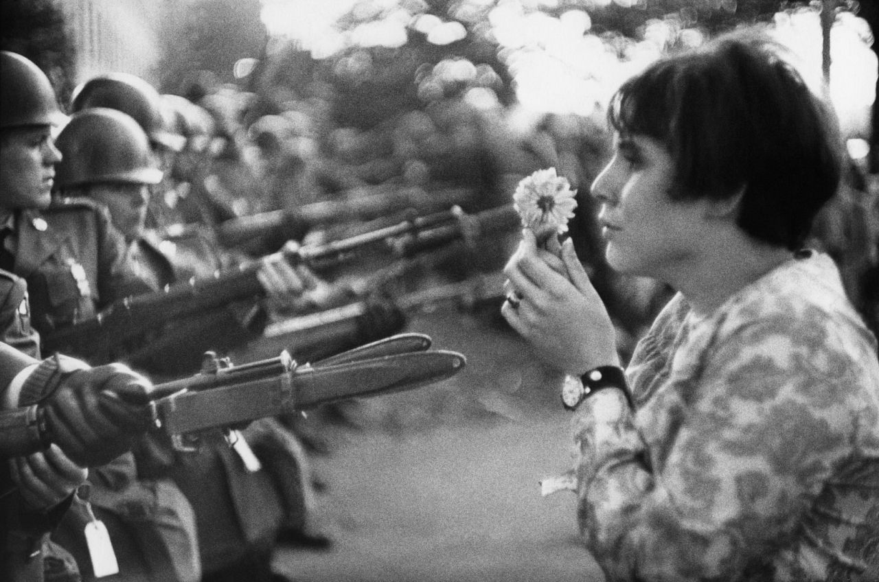 A woman offers a flower to a group of soldiers.