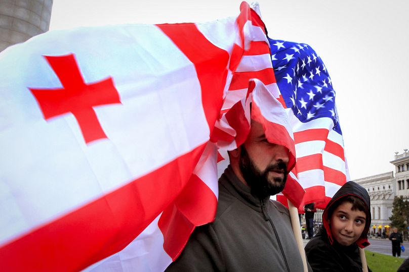 Un uomo e un ragazzo tengono in mano bandiere georgiane e statunitensi durante una manifestazione dell'opposizione, Tbilisi, Georgia, 20 ottobre 2024