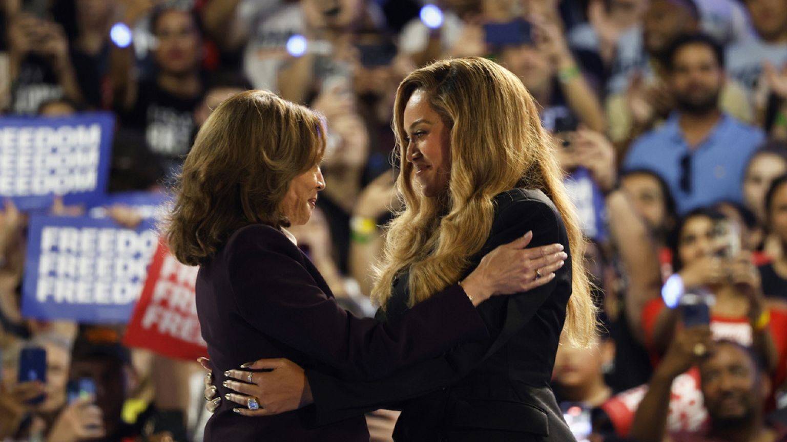 A artista musical Beyoncé, à direita, e a candidata democrata à presidência, a vice-presidente Kamala Harris, à esquerda, abraçam-se no palco durante um comício de campanha na sexta-feira, 25 de outubro de 2024,