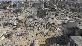 Palestinians walk through the destruction left by the Israeli air and ground offensive on the Gaza Strip.